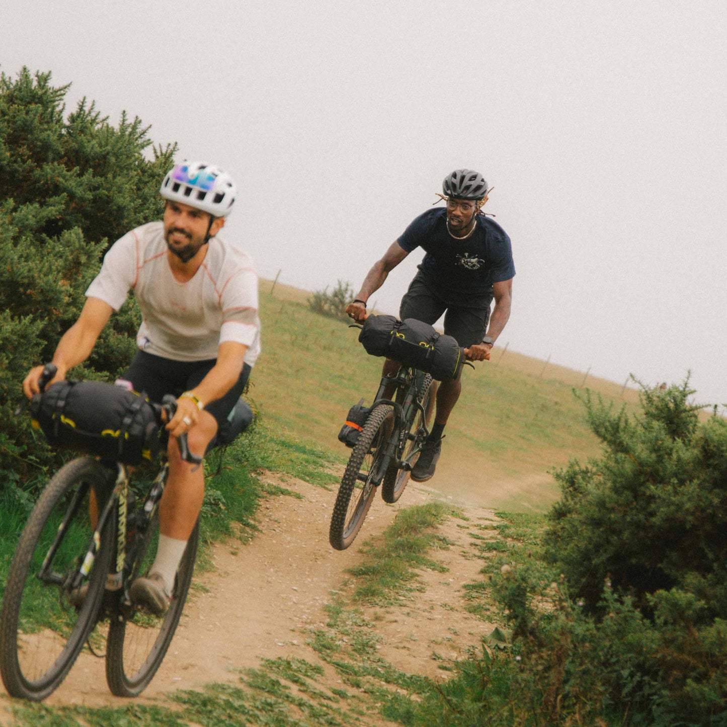 Two cyclists on a dirt path surrounded by greenery