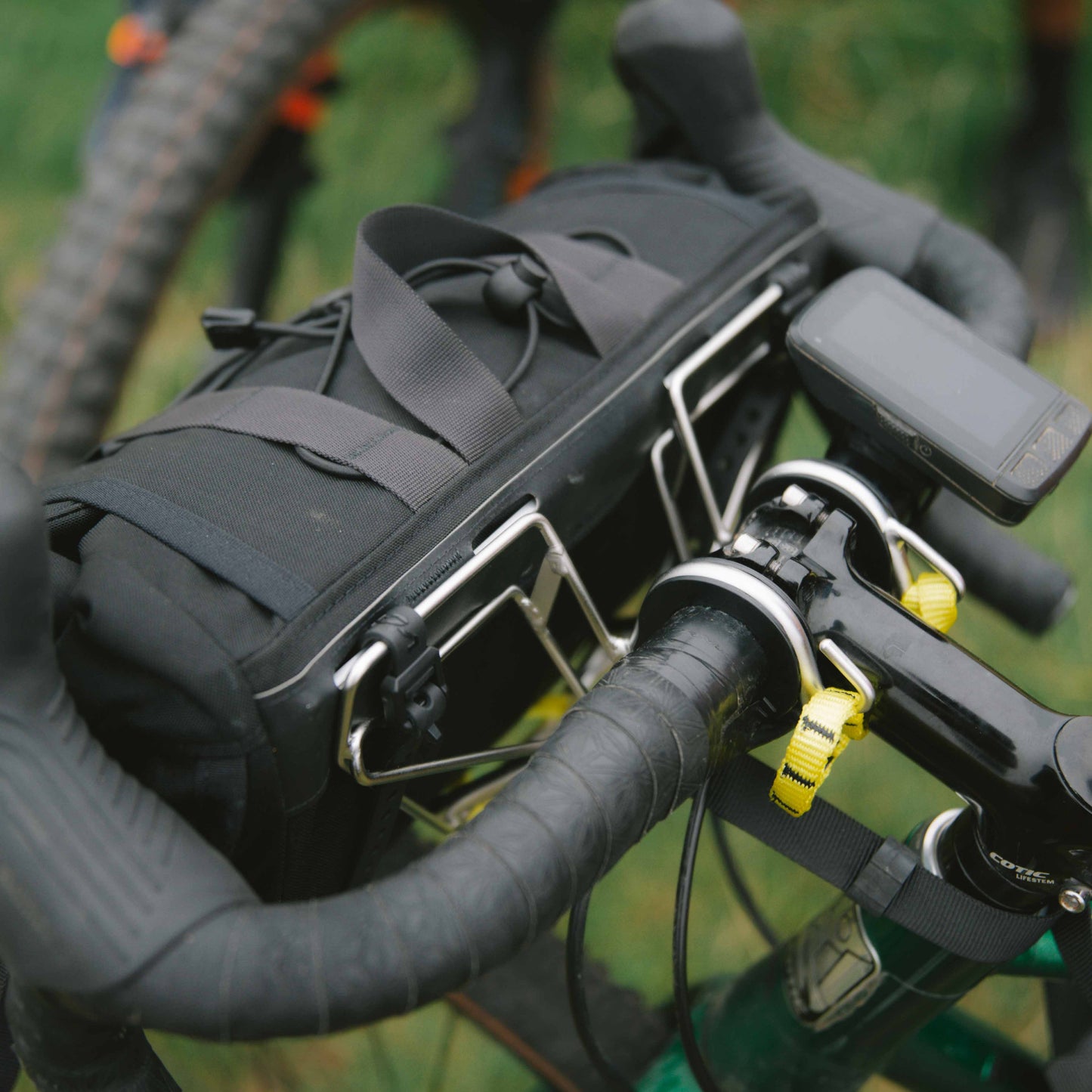 Bicycle handlebar with a black bag attached, blurred background