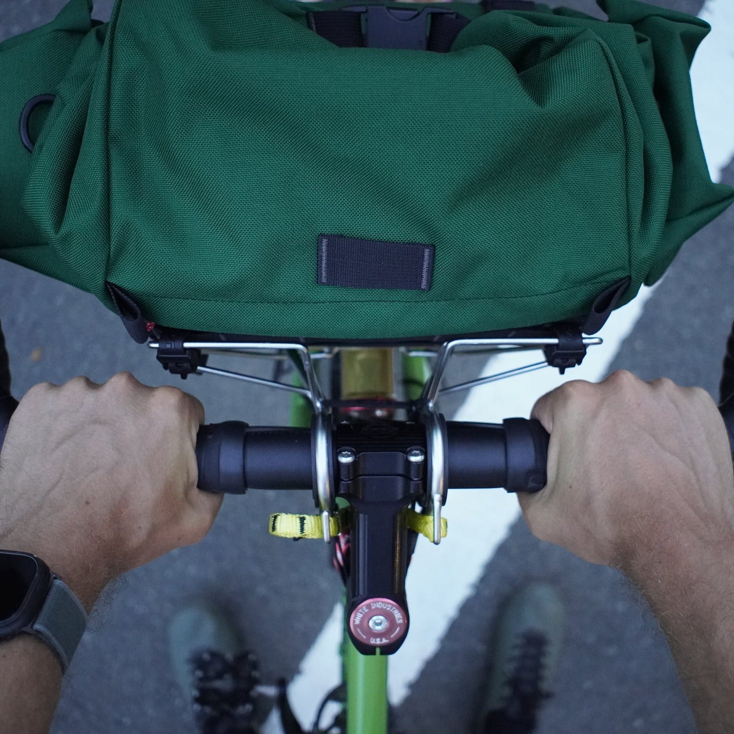 Person holding a green bag with handlebars and a watch on wrist